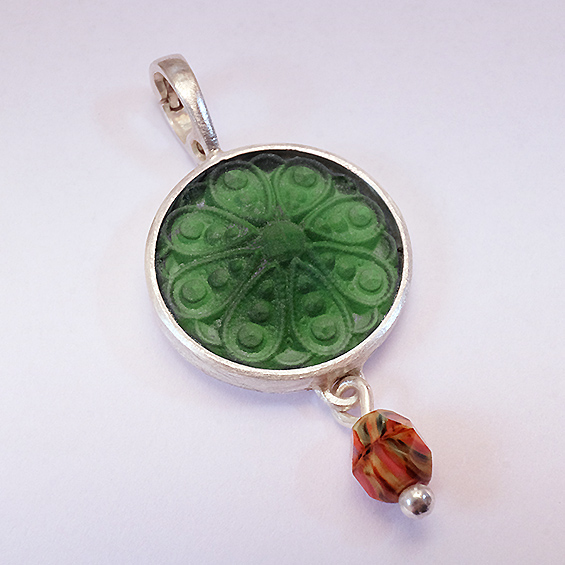 Klappanhänger Retroglas Anhänger mit grünem, blumenförmigem Design und einer roten Perle.