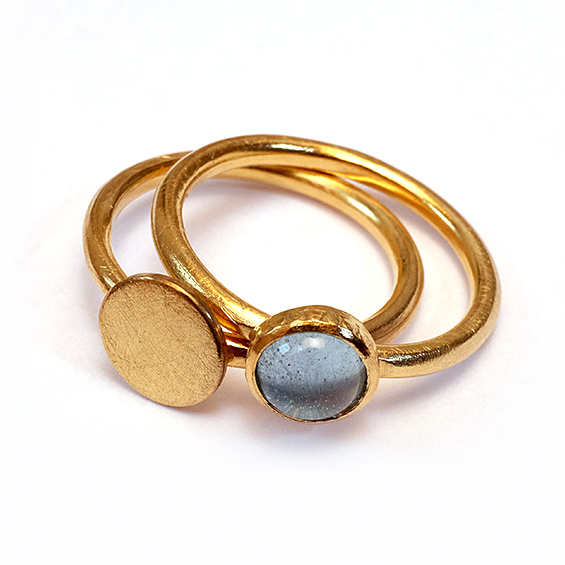 Feinlein Ringe Zwei goldene Ringe, einer mit flacher Oberfläche und einer mit einem blauen Stein.