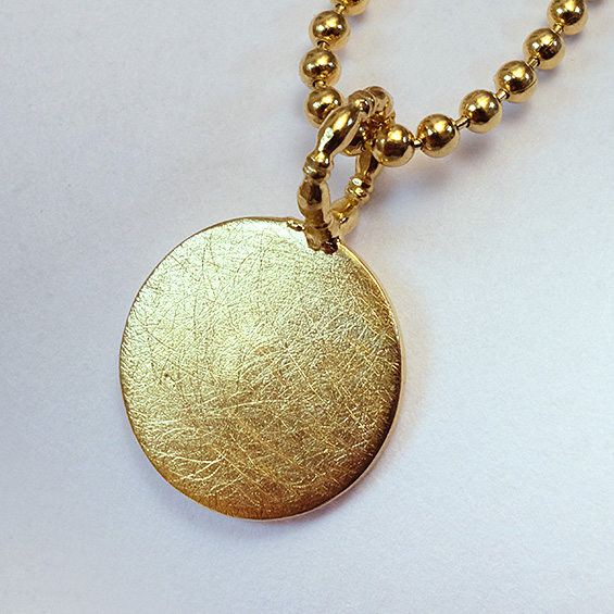 Ketten-Anhänger Goldener Anhänger mit strukturierter Oberfläche, an einer kleinen Perlenkette aufgehängt.